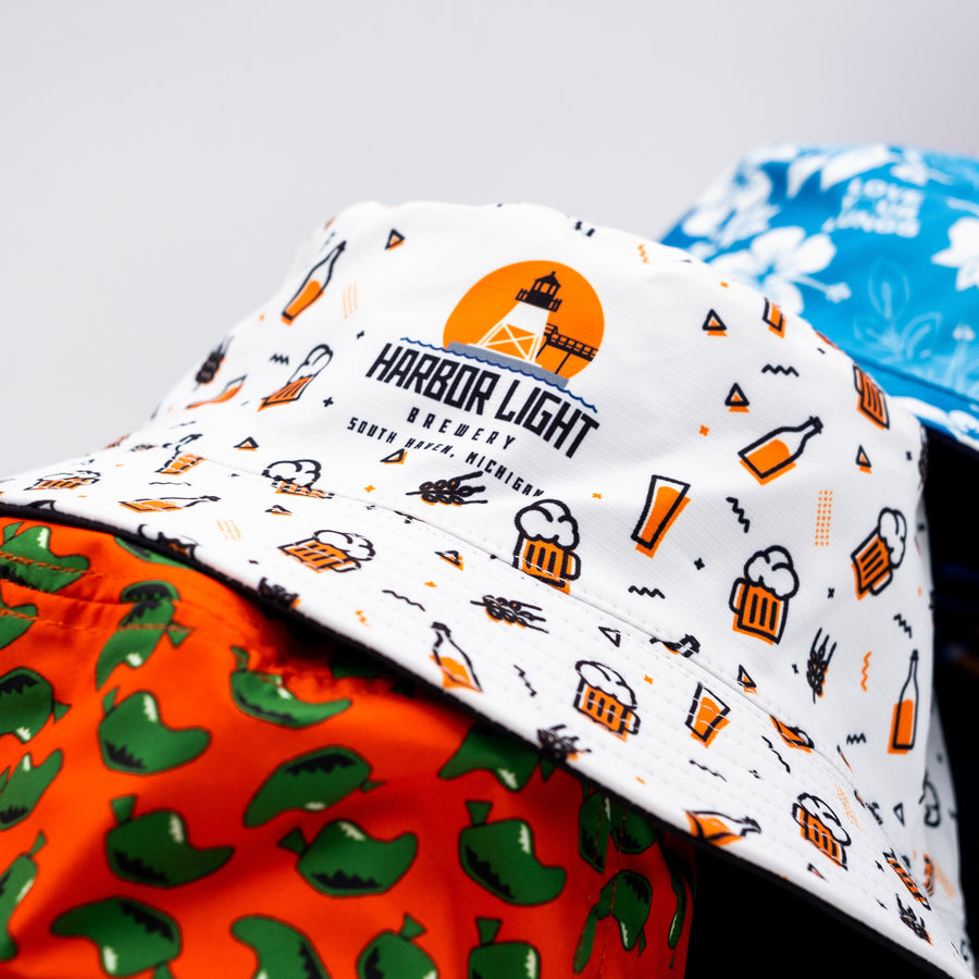 Stack of custom printed bucket hats with branded designs including Harbor Light Brewery – Roody custom bucket hats Ireland